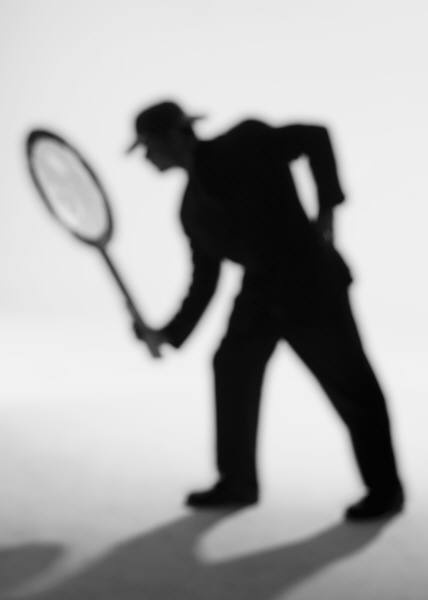 A man dressed in a suit holds a magnifying glass